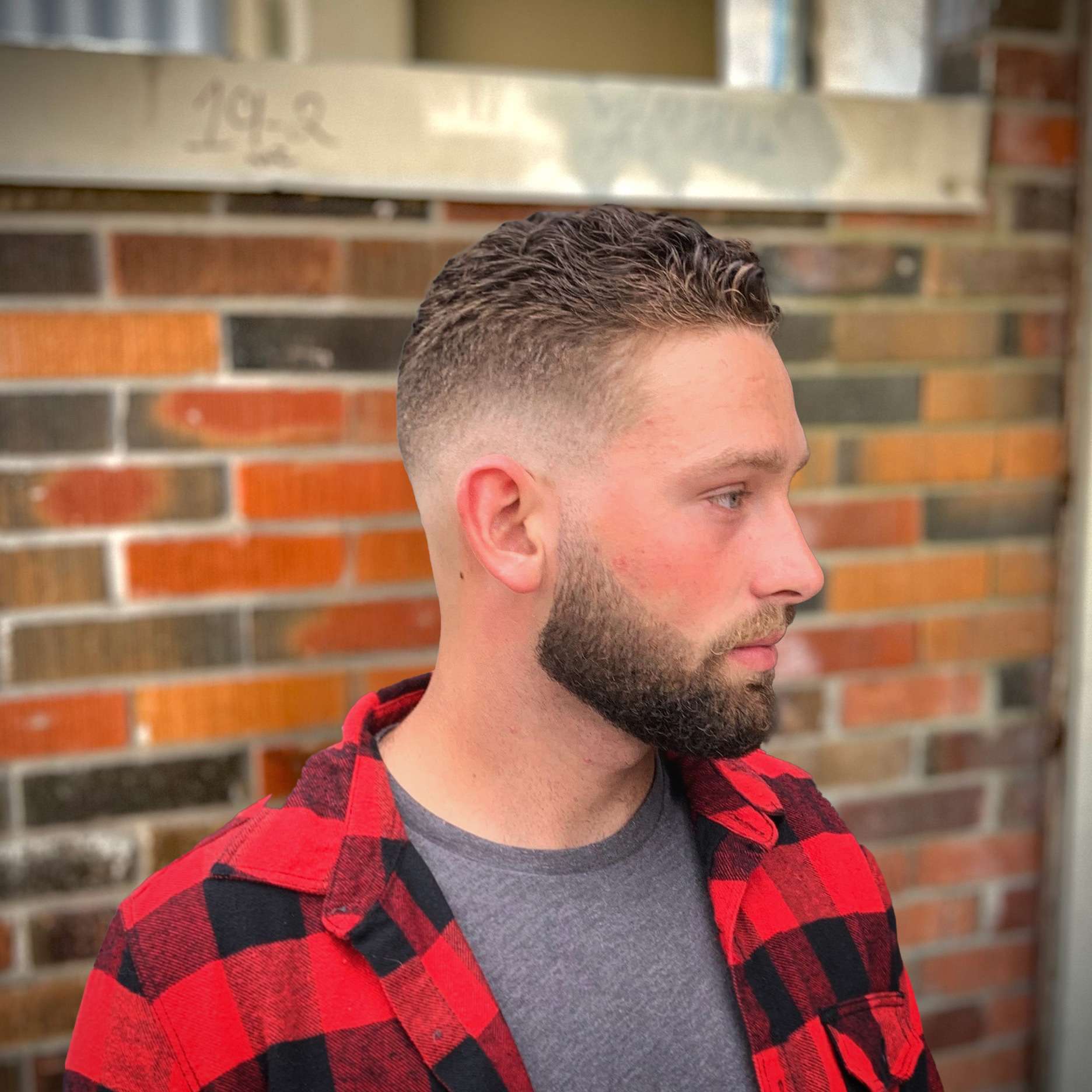 Man with a high skin fade, curly top and beard trim