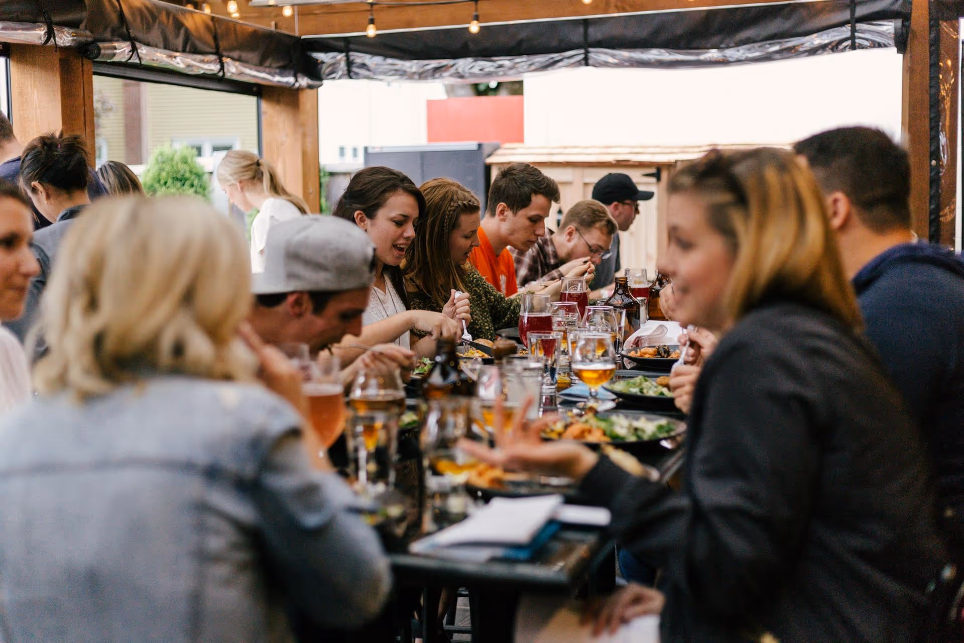 A person is cutting into grilled chicken on a plate with bulgur, sliced onions, and grilled vegetables. Nearby are dishes of olives and feta with walnuts, creating a vibrant, appetizing scene.