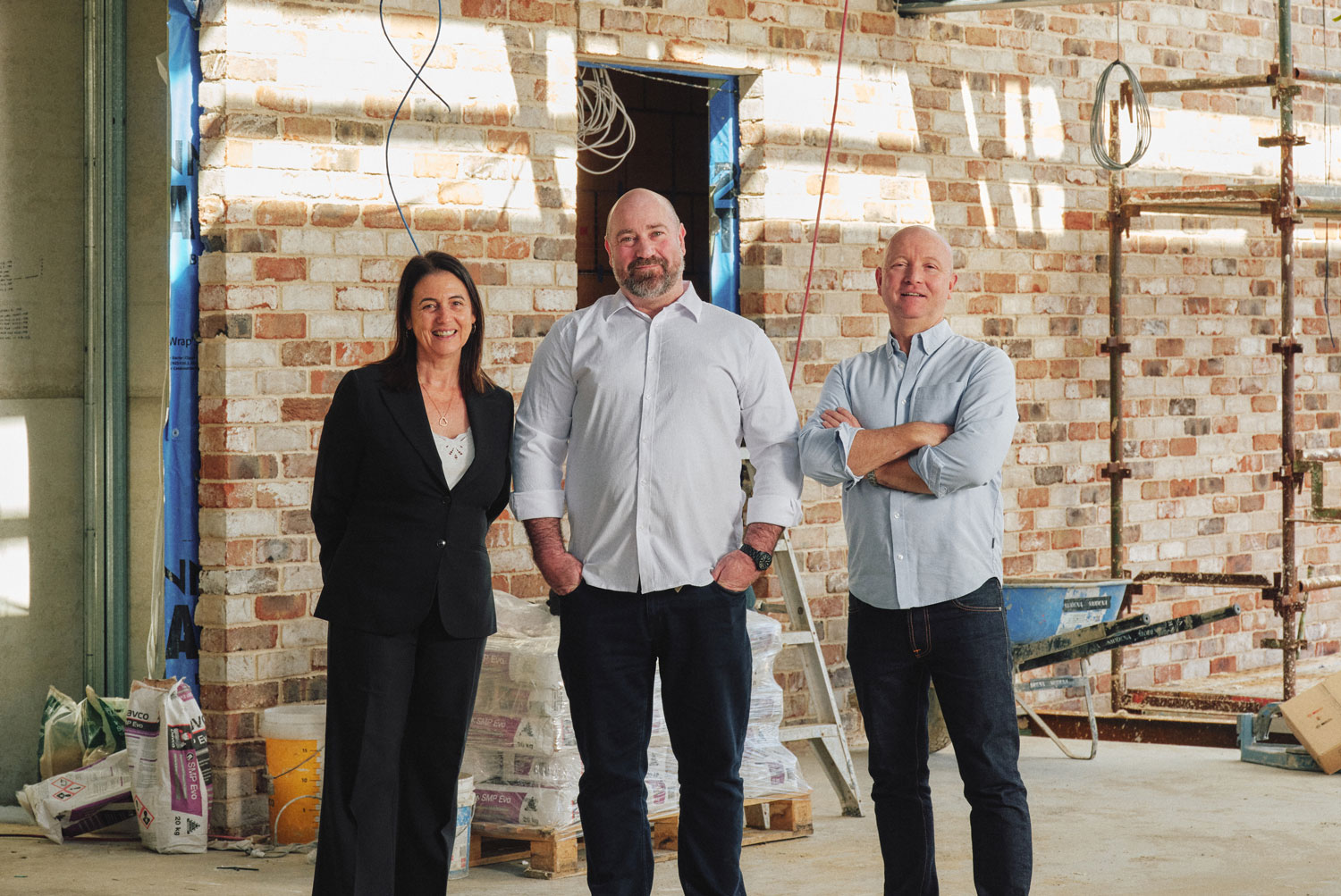Three people set a table for an elegant event, arranging flowers and napkins. The atmosphere is focused and collaborative in a well-lit venue.