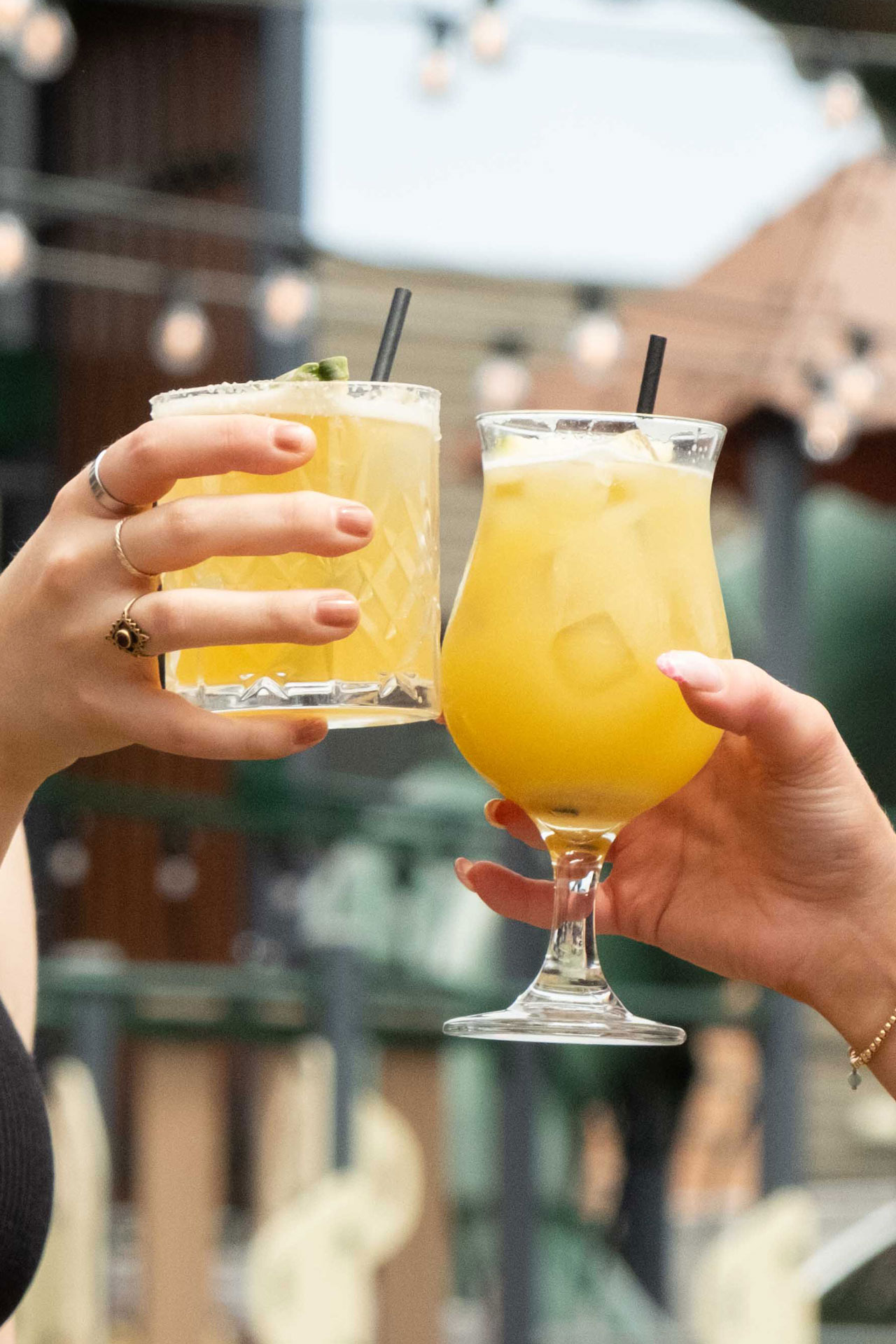 Two hands clink champagne glasses in a warm, dimly lit setting. A candle flickers in the background, adding a festive, celebratory mood.