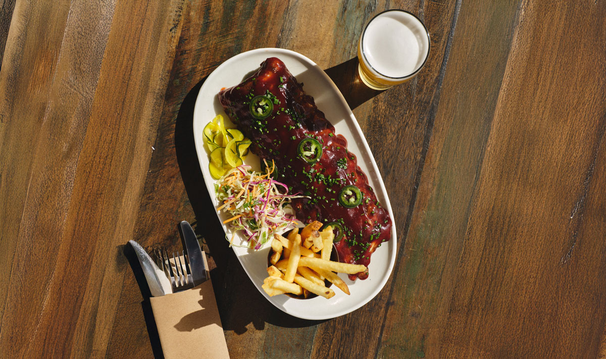 A vibrant spread of diverse dishes on colorful plates: soup with greens, stuffed pastries, bread with egg, dips, and garnished meats on rustic surfaces.