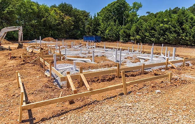 A house under construction with a visible foundation and a crane working on the site.