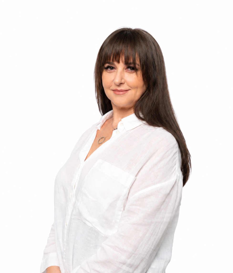 Professional portrait of a woman wearing a sleeveless white blouse and black pants, standing confidently against a clean white background.