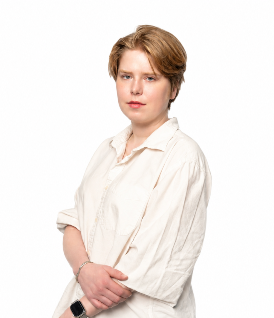Professional portrait of a woman wearing a sleeveless white blouse and black pants, standing confidently against a clean white background.