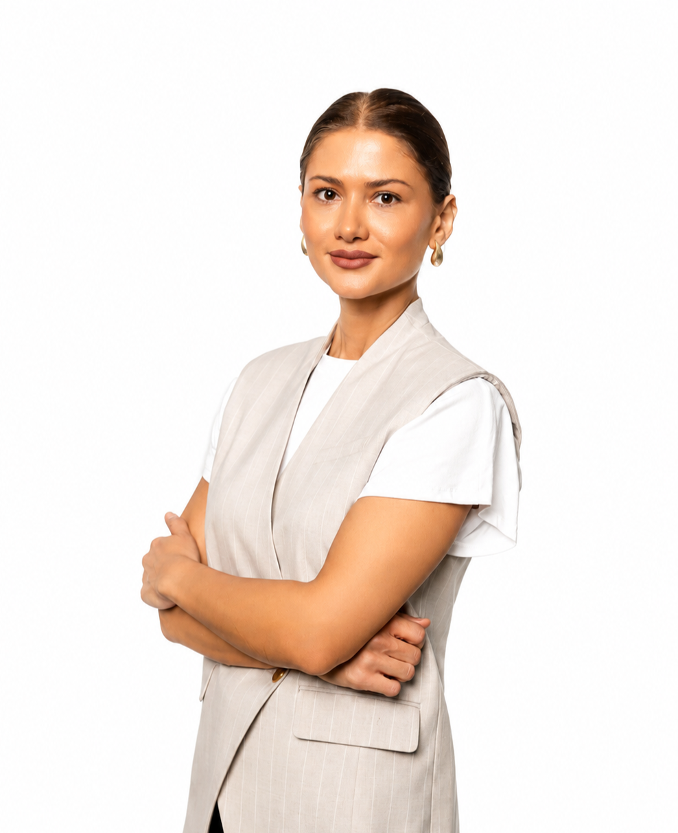Professional portrait of a woman wearing a sleeveless white blouse and black pants, standing confidently against a clean white background.