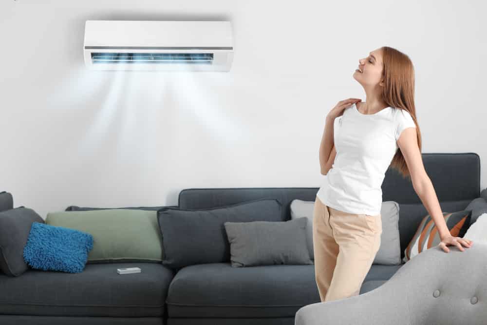 young woman enjoying cool air from air conditioner