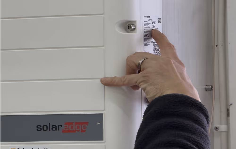 Bild på en elcentral där en elektriker drar fingret över en instruktionsmärkning för att läsa vad som står. 