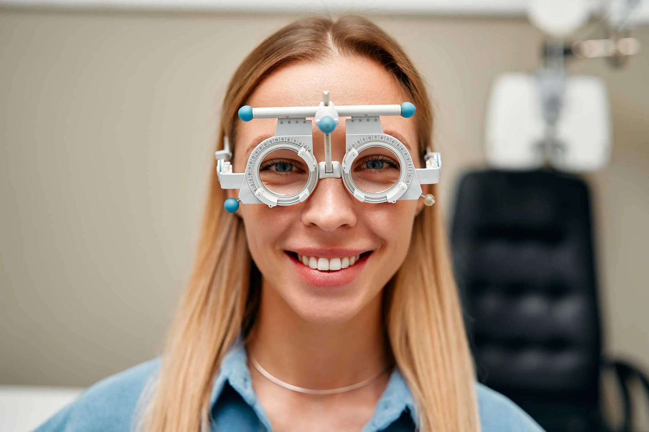 Smiling woman wearing optometry trial frame during eye exam