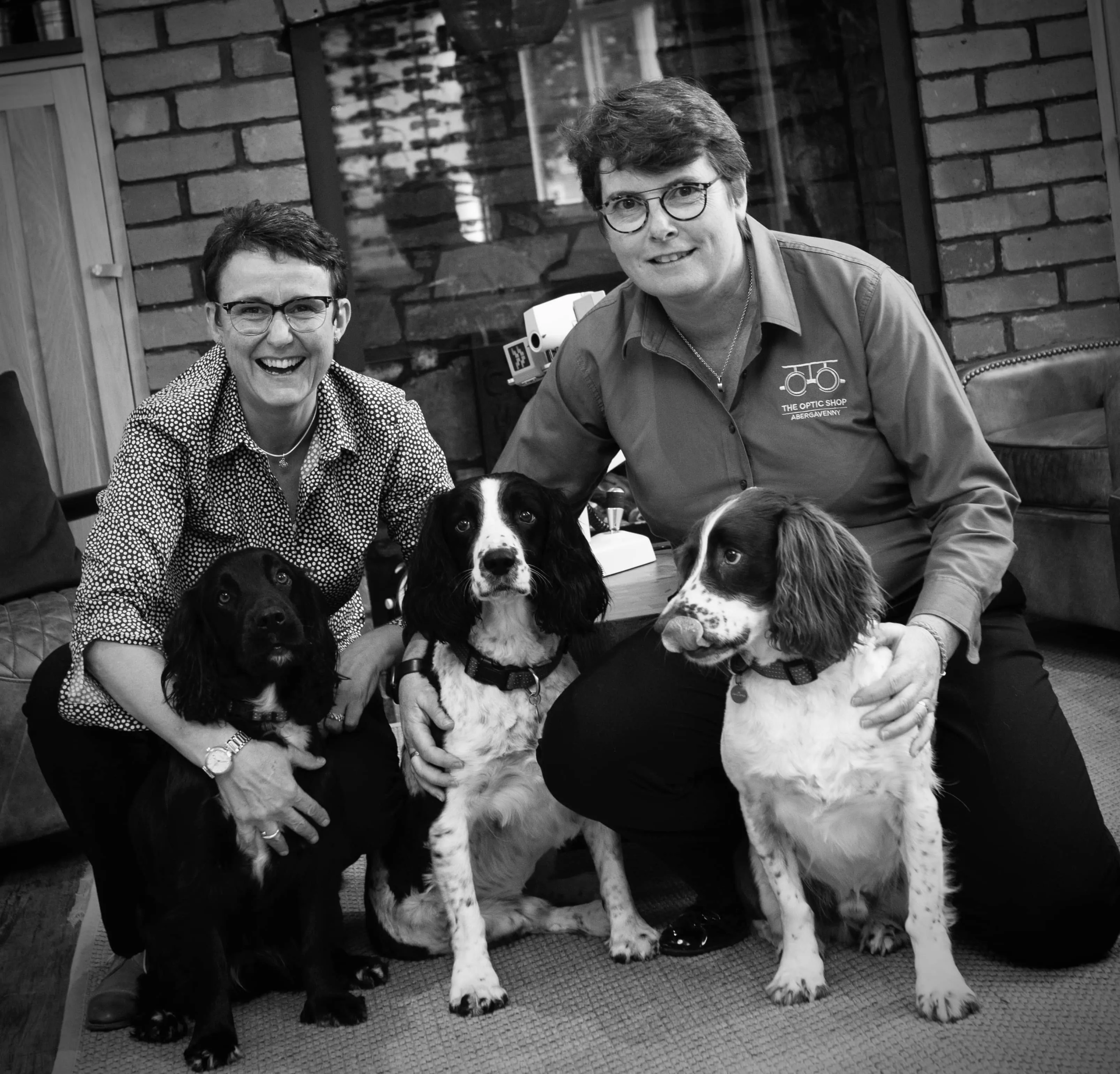 Two people smiling with three dogs in black and white photo