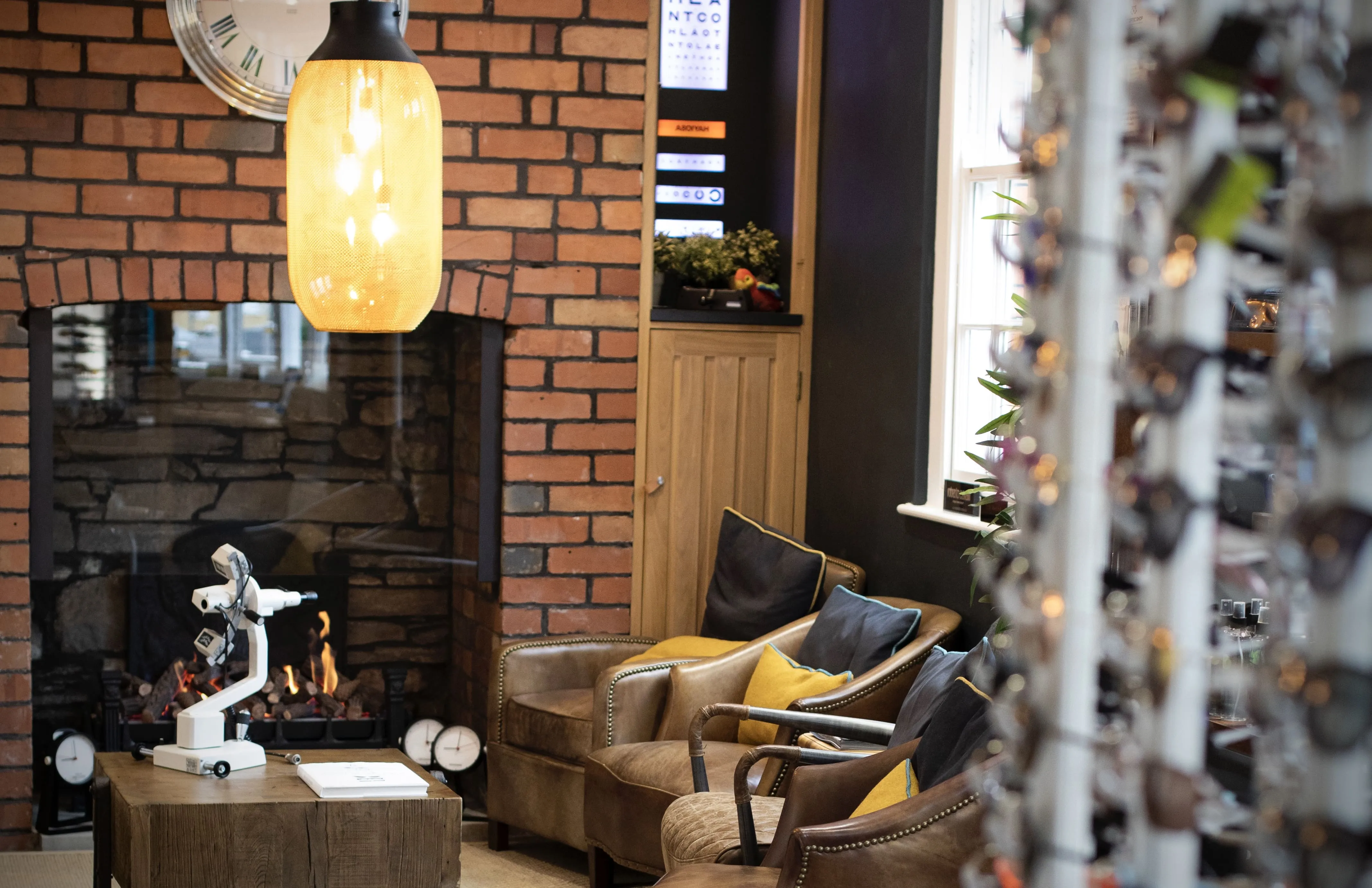 Cozy living room with brick wall, fireplace, leather chairs, and yellow lamp