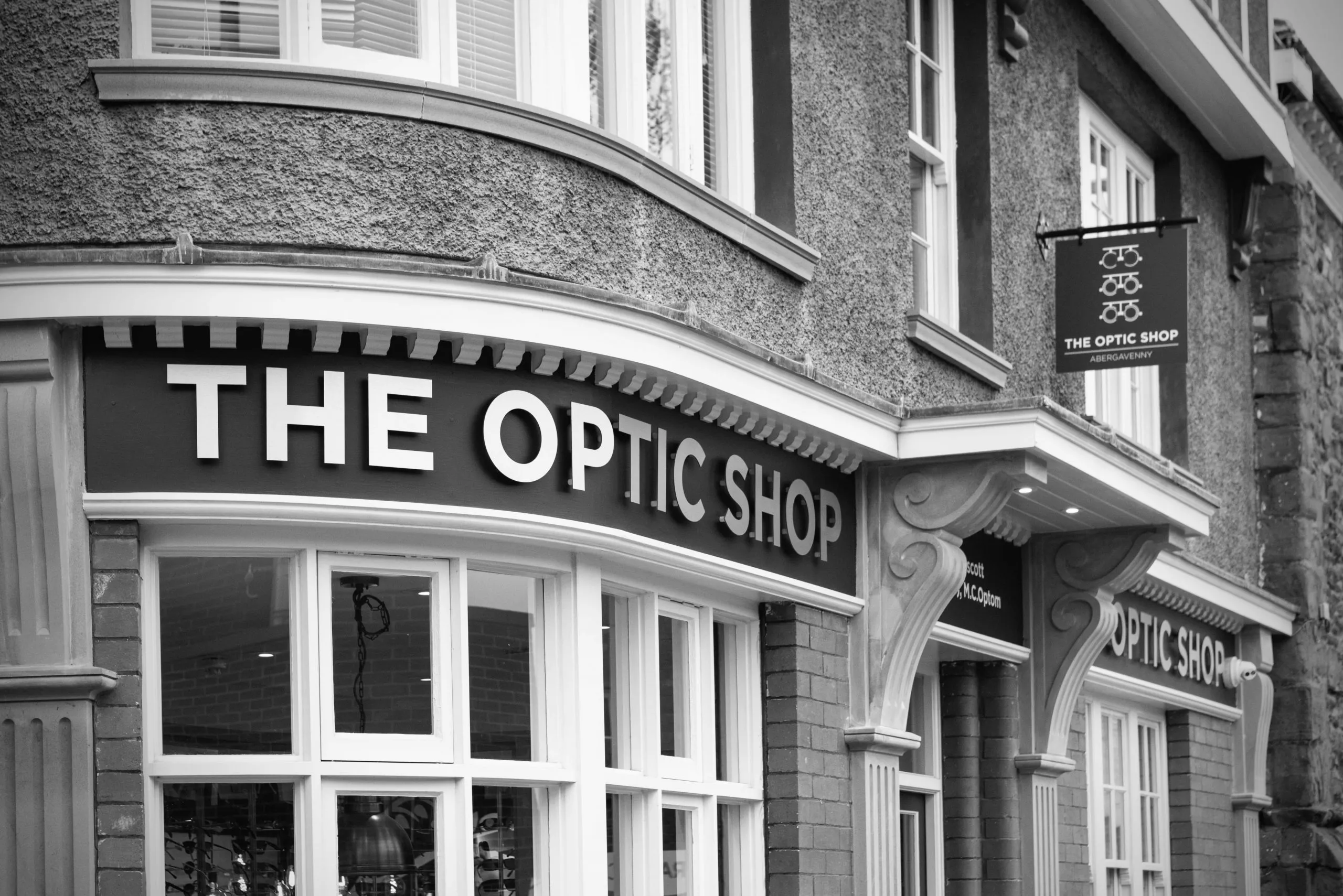Black and white exterior of The Optic Shop storefront with signage