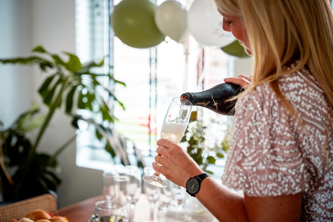 Gast van een trouwfeest schenkt cava in haar glas.
