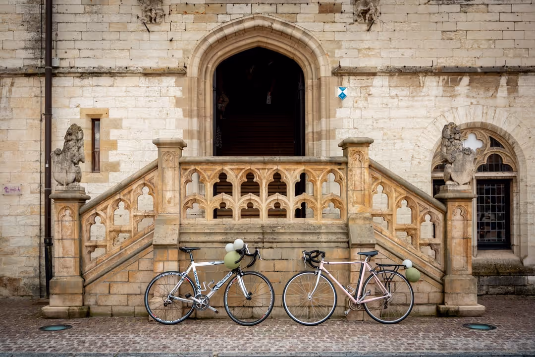 Ingang van een gemeentehuis met daarvoor 2 koersfietsen met ballonnen eraan.