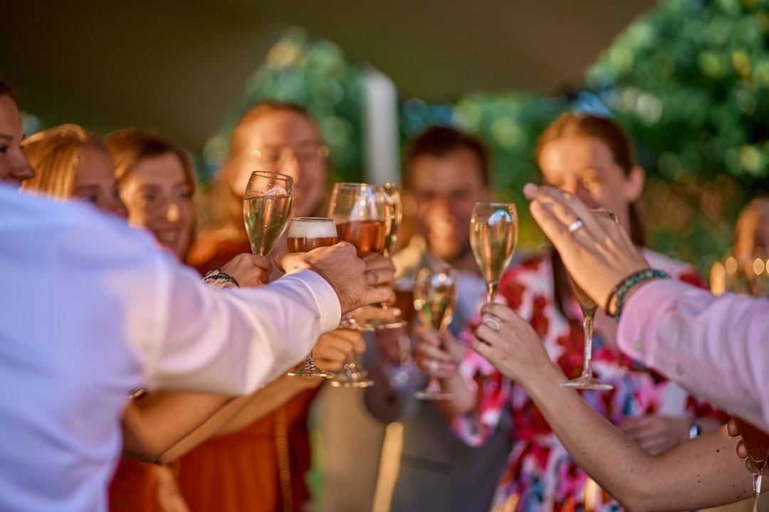 Gasten op een trouwfeest hebben hun wijnglas in de hand en klinken met elkaar.