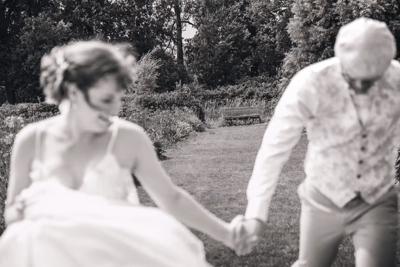 Close-up van het bruidspaar dat hand in hand naar de cameralens loopt.