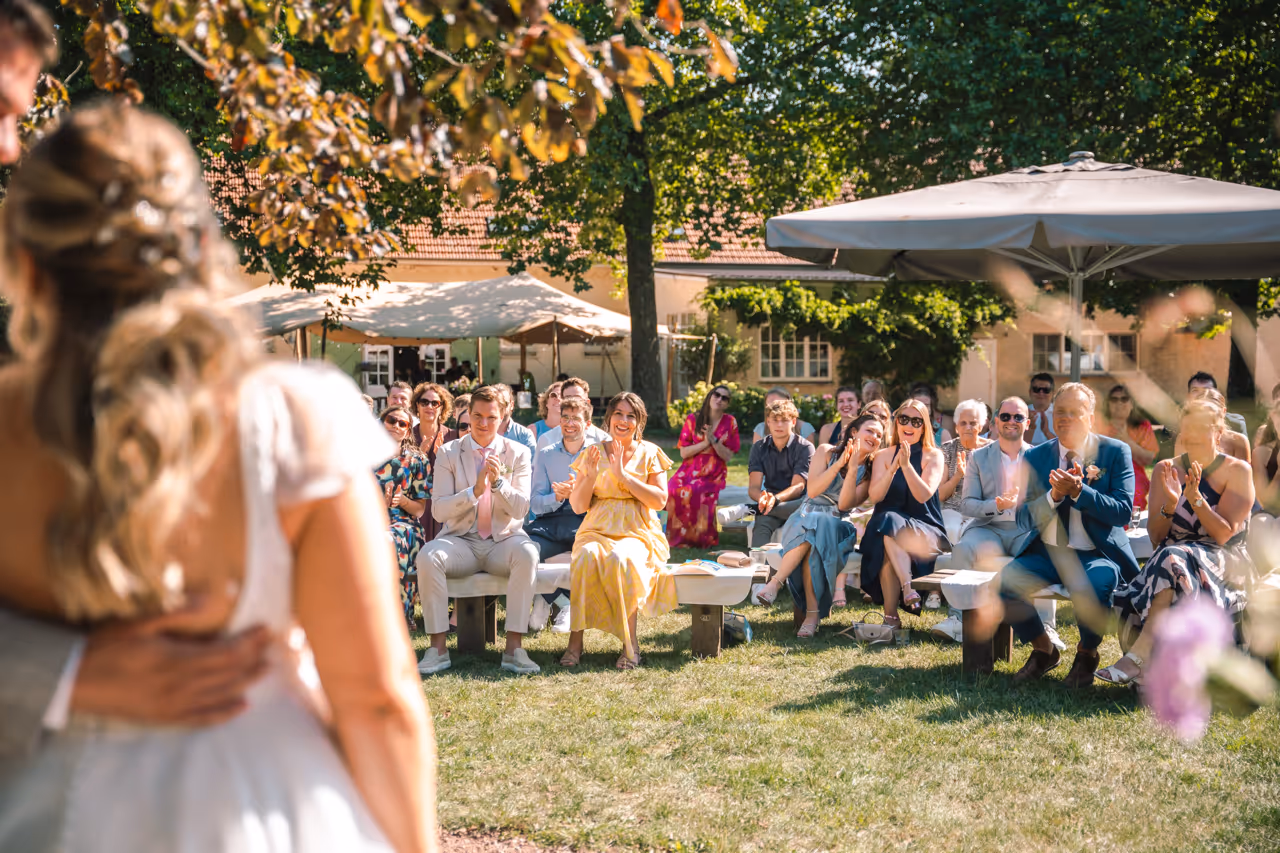 De gasten applaudiseren tijdens de trouwceremonie.