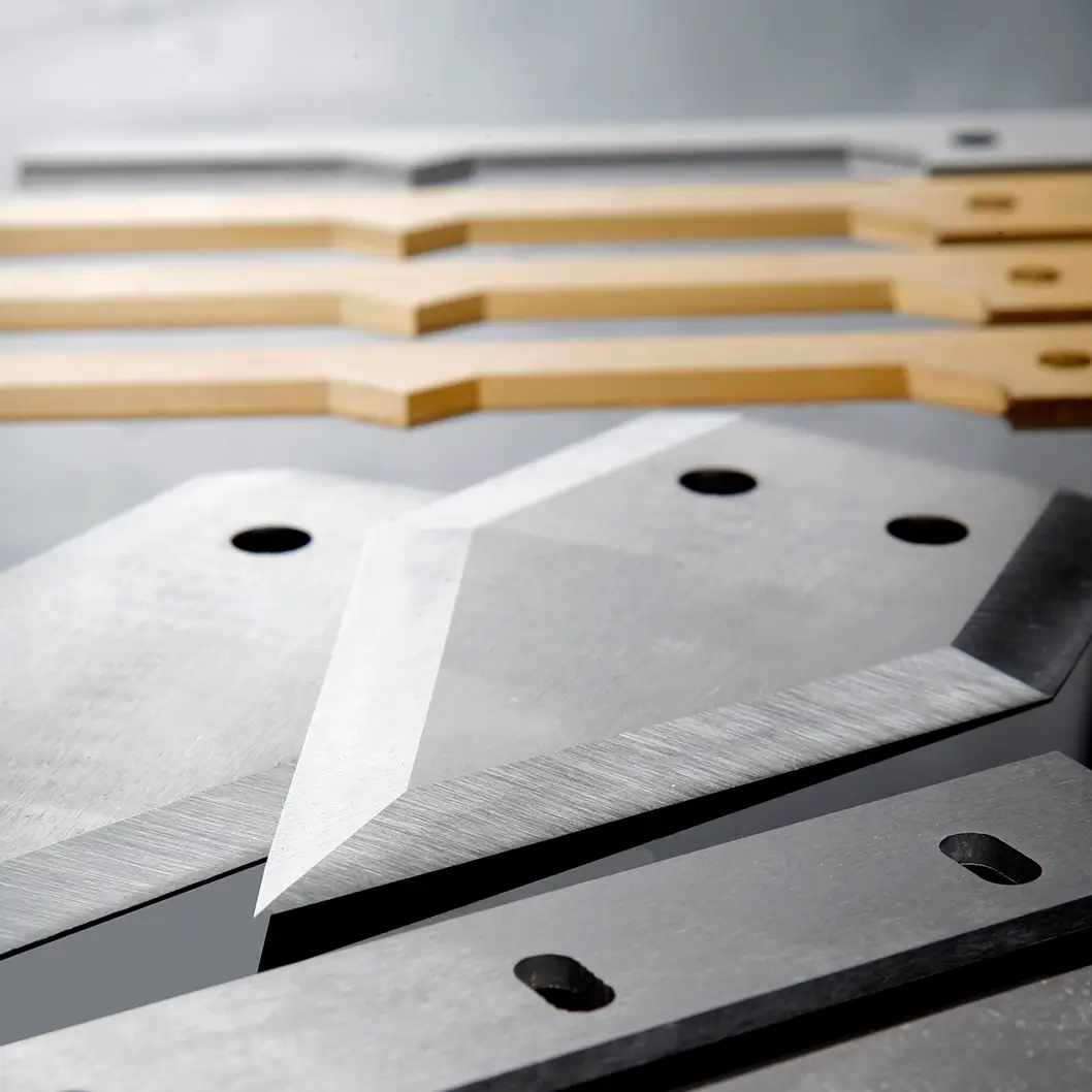 Close-up of machine blades, including steel and gold coated finishes, manufactured by Durham Duplex for heavy-duty cutting applications.