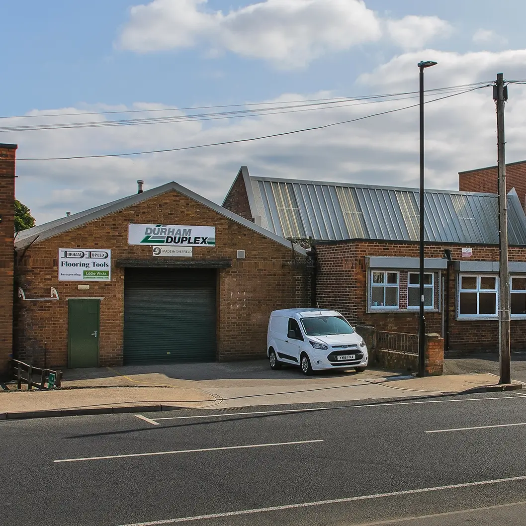 Exterior view of Durham Duplex's building with a company signage and white van parked outside.