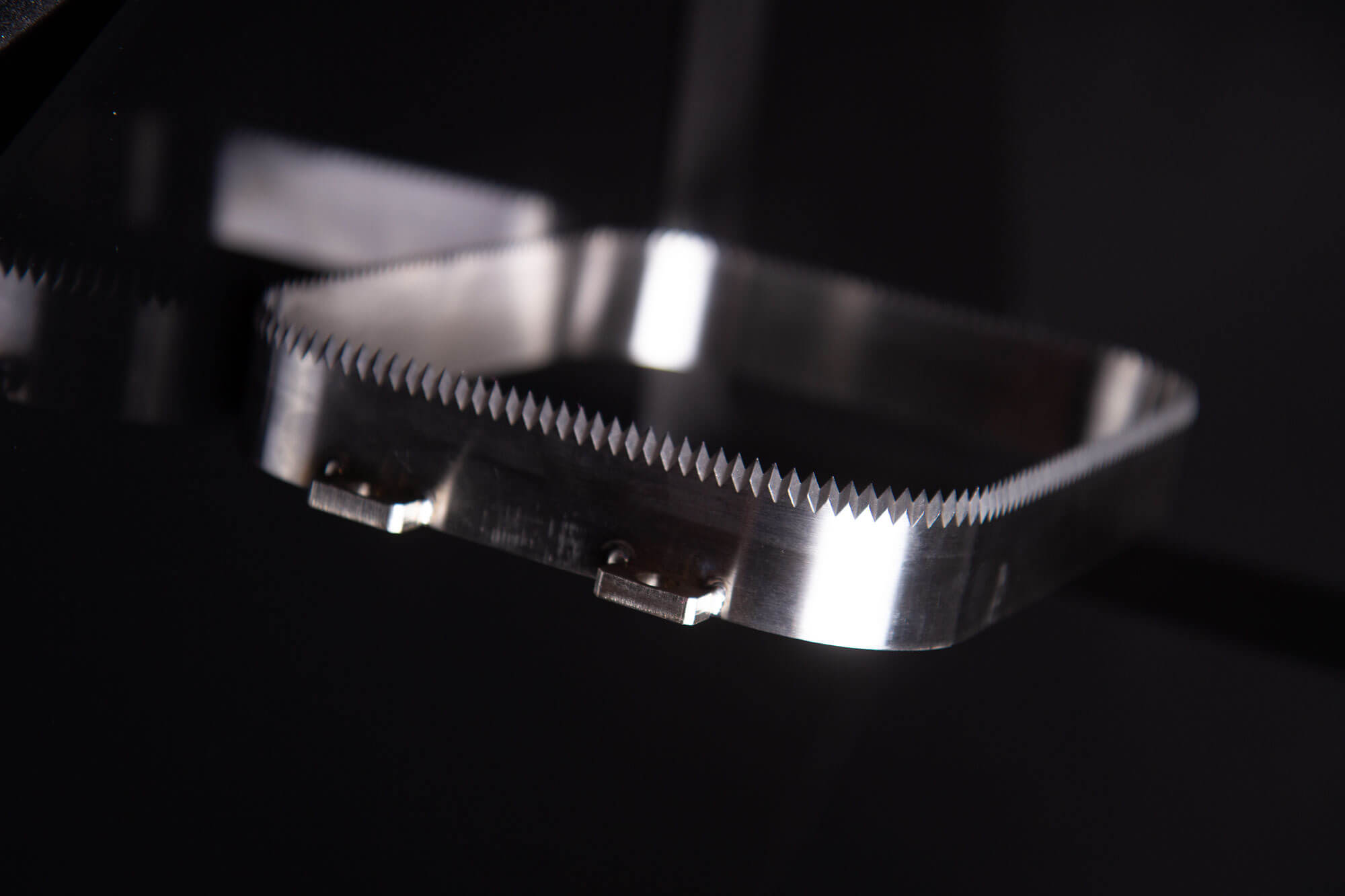 Close-up of a stainless steel tray knife with fine serrated edges used for packaging, manufactured by Durham Duplex.