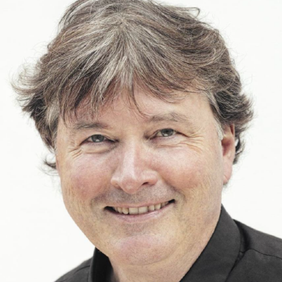 Smiling middle-aged man with graying hair wearing a black shirt on a white background.
