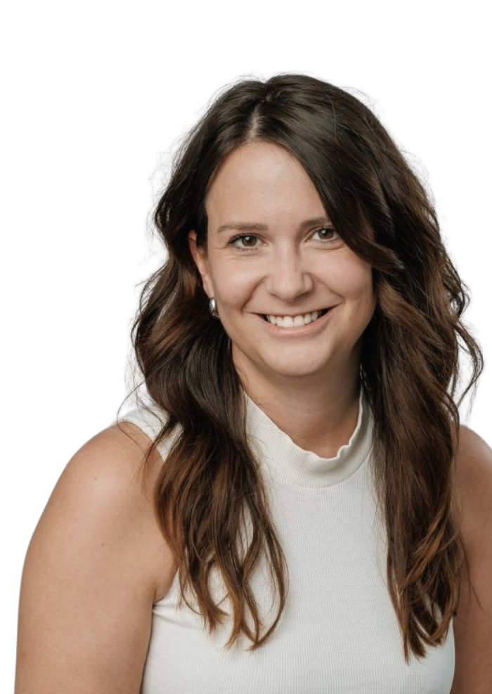 Smiling woman with long brown hair wearing a white sleeveless top and pearl earrings.