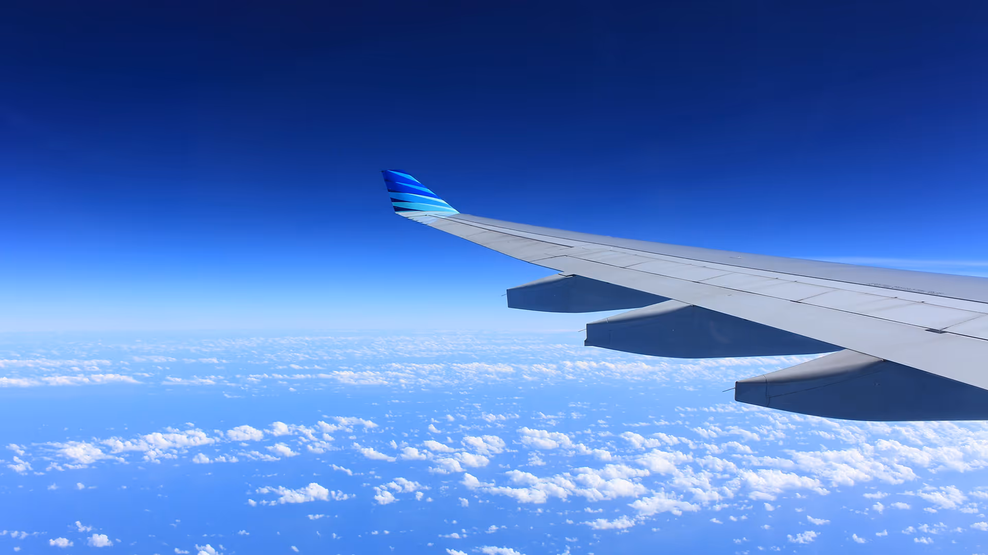 Airplane wing and clouds viewed from a window during a flight