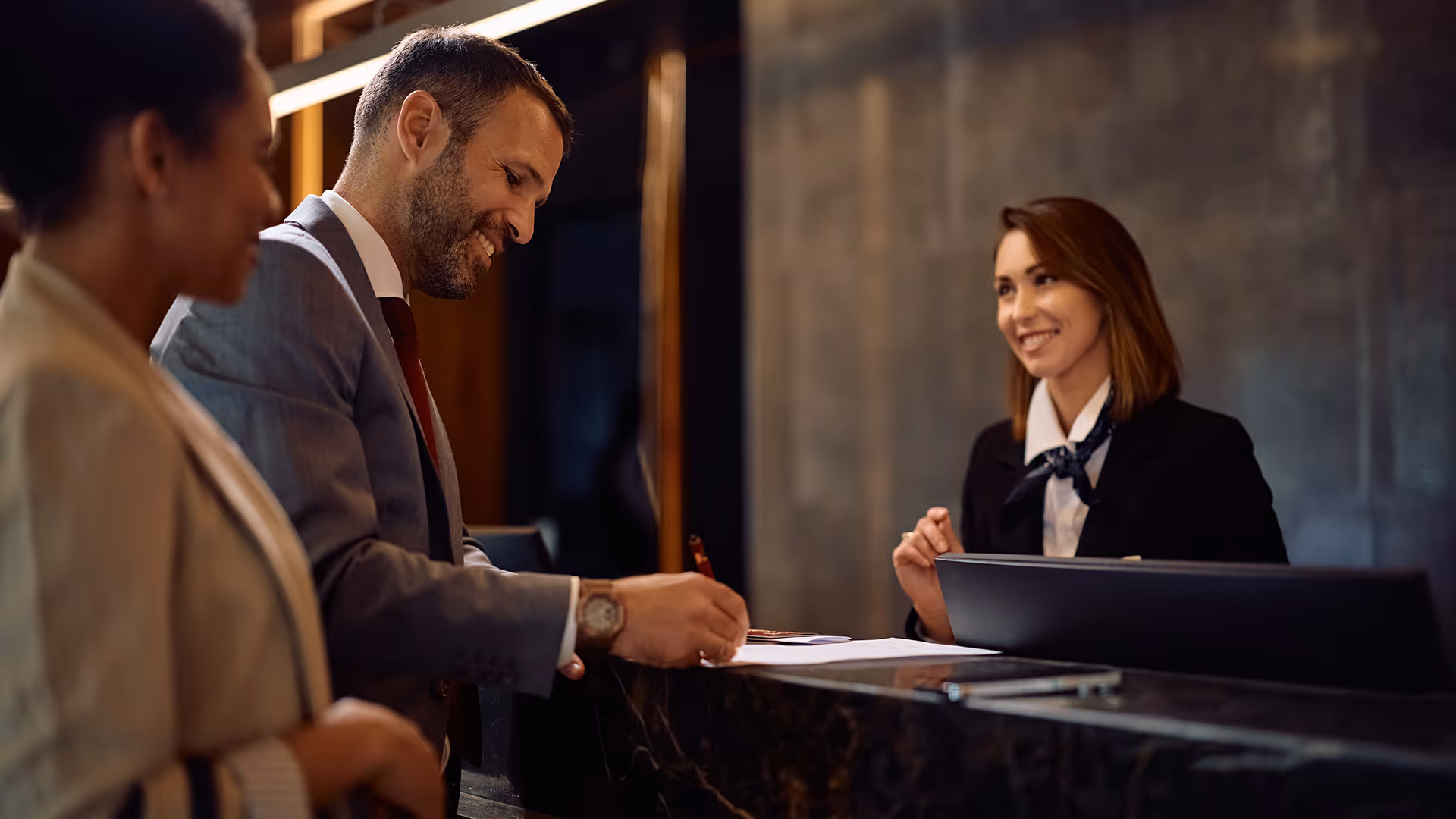 Man signing paperwork at a hotel, representing payment processing for accommodation providers