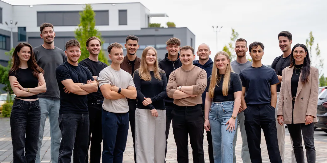 Das PimpUP Team draußen vor dem Büro auf dem Parkplatz, Gruppenfoto der Mitarbeiter