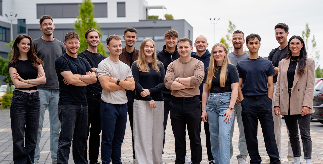 Das PimpUP Team draußen vor dem Büro auf dem Parkplatz, Gruppenfoto der Mitarbeiter