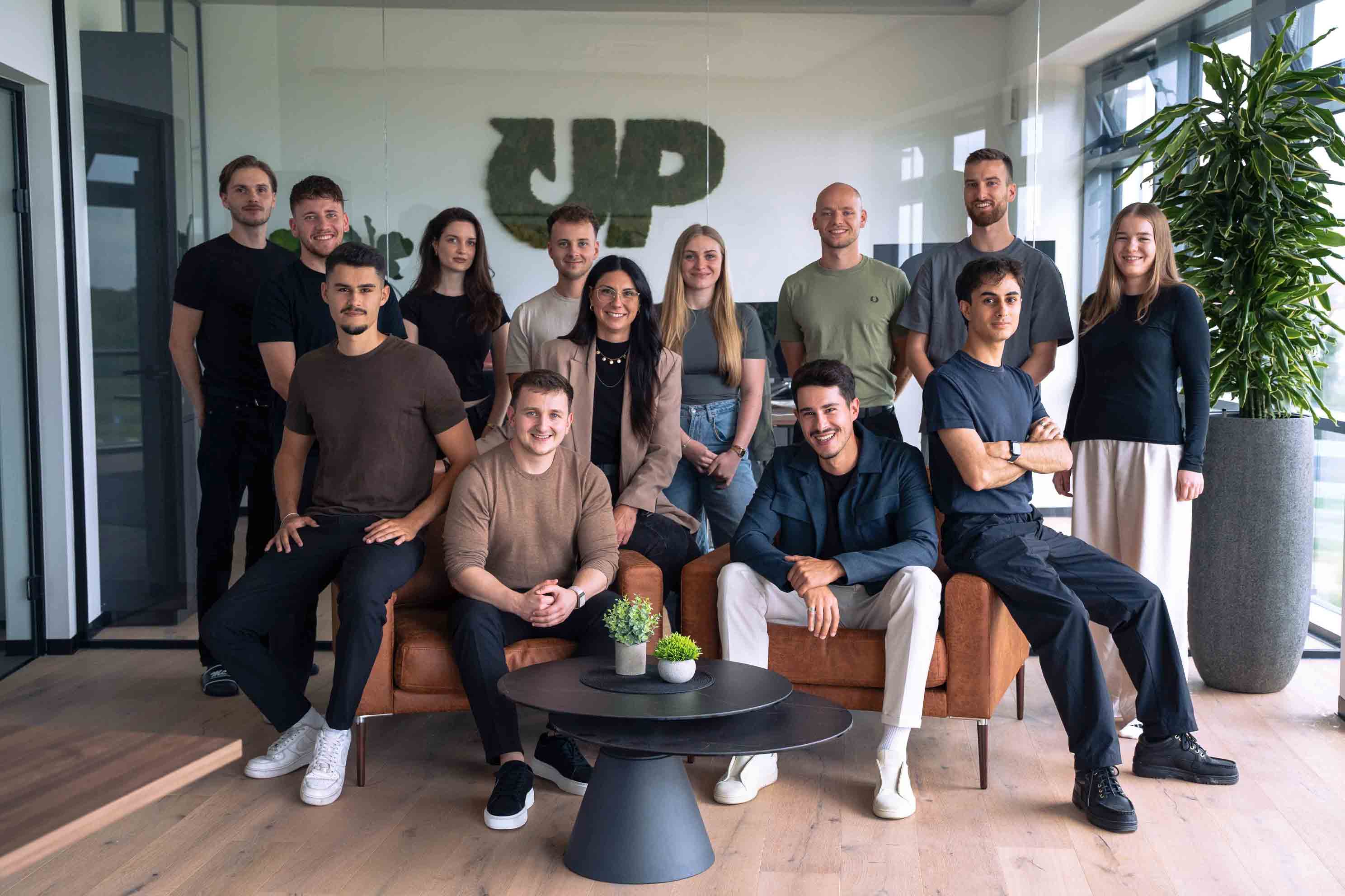 Gruppenfoto des PimpUP Teams im Büro vor dem Firmenlogo