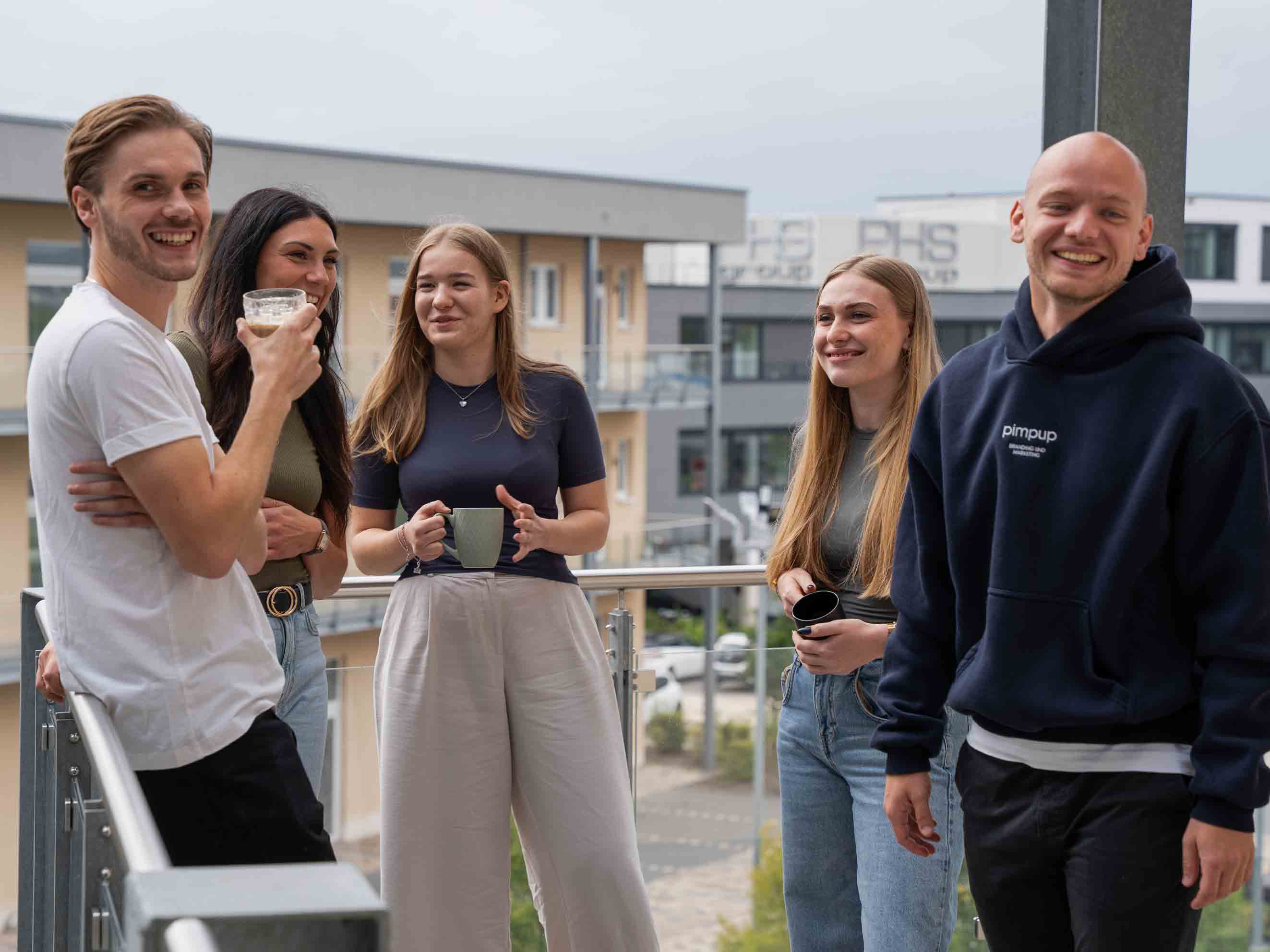 Das PimpUP Team lacht gemeinsam auf dem Büro-Balkon in entspannter Atmosphäre