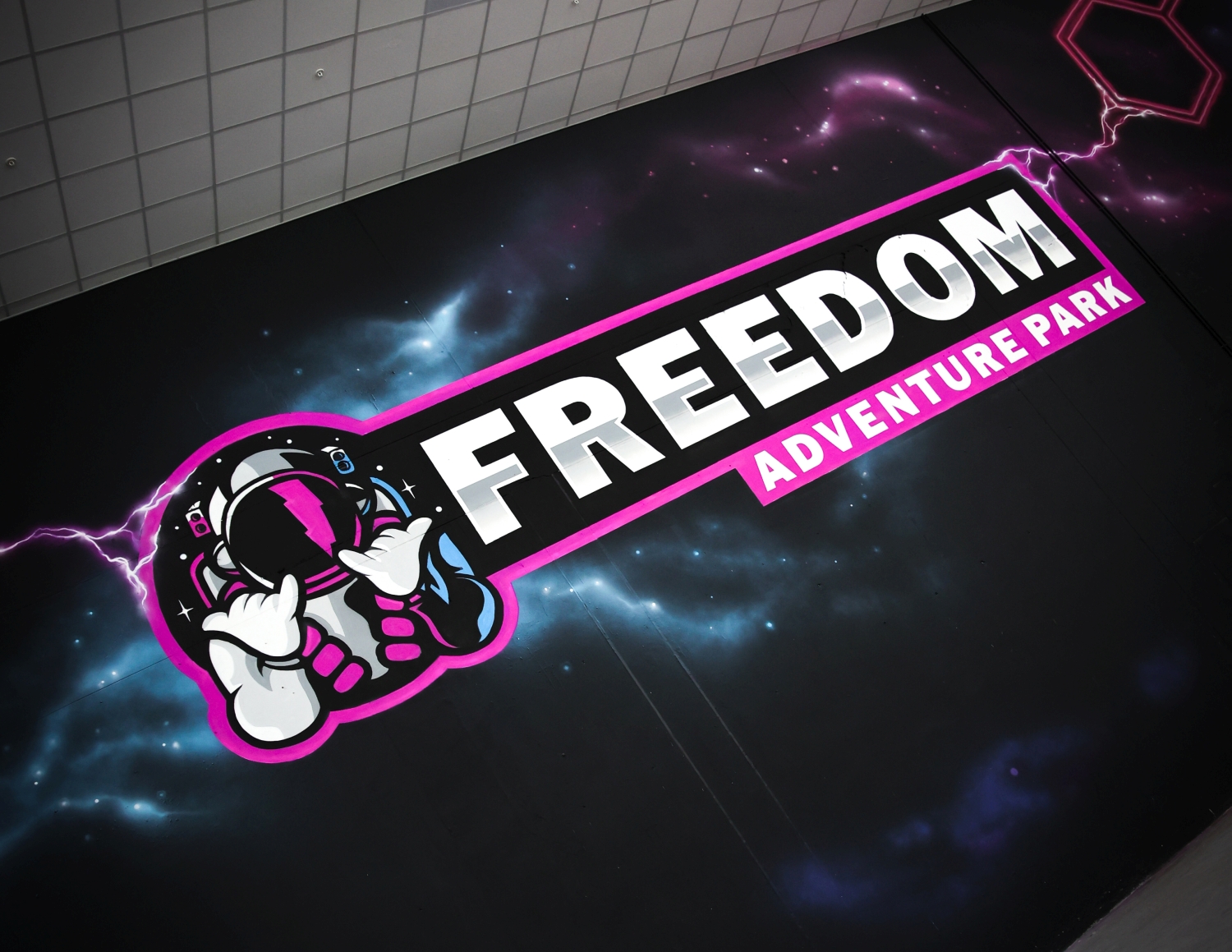 Logo of Freedom Adventure Park featuring an astronaut with a lightning bolt on the helmet and cosmic background.