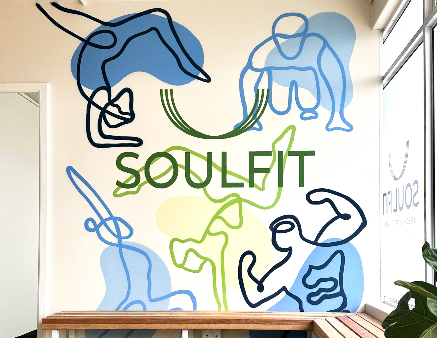Wall mural with abstract line drawings of fitness poses in blue and green with the word SOULFIT in green letters.