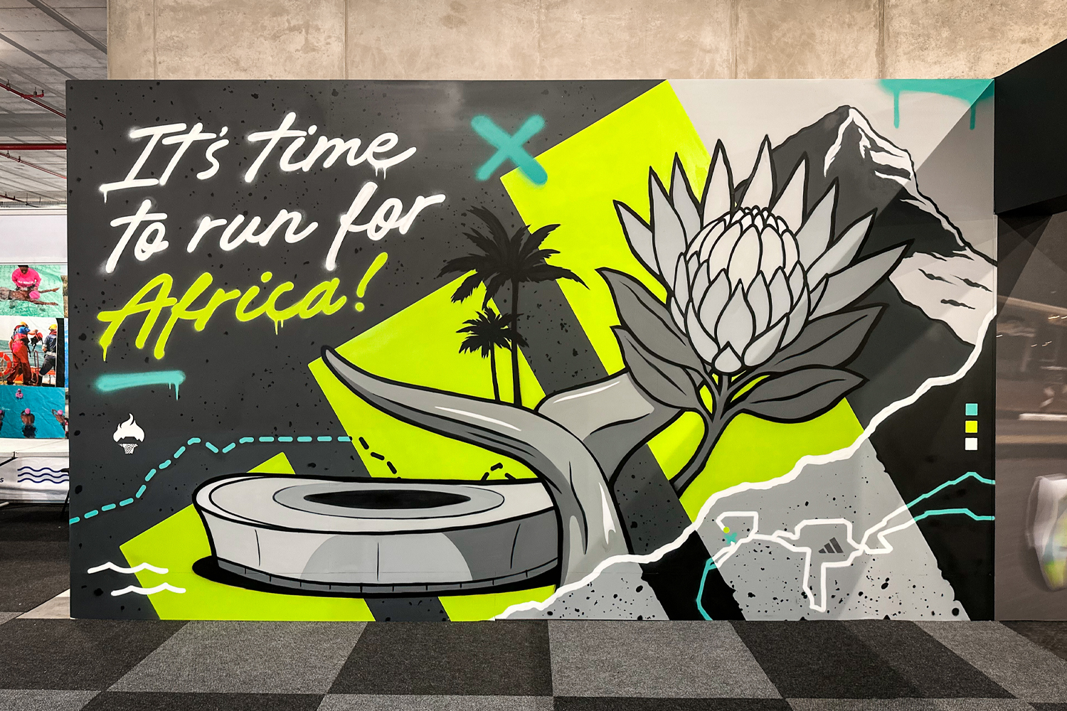 Mural with text 'It's time to run for Africa!' featuring stylized elements like a flower, palm trees, a mountain, and a circular structure on a vibrant green and gray background.