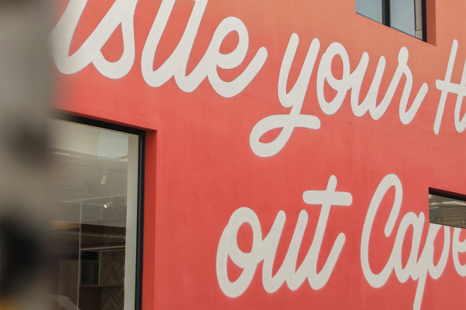 Close-up of a red wall with large white cursive text saying 'Use your H... out Cape...'