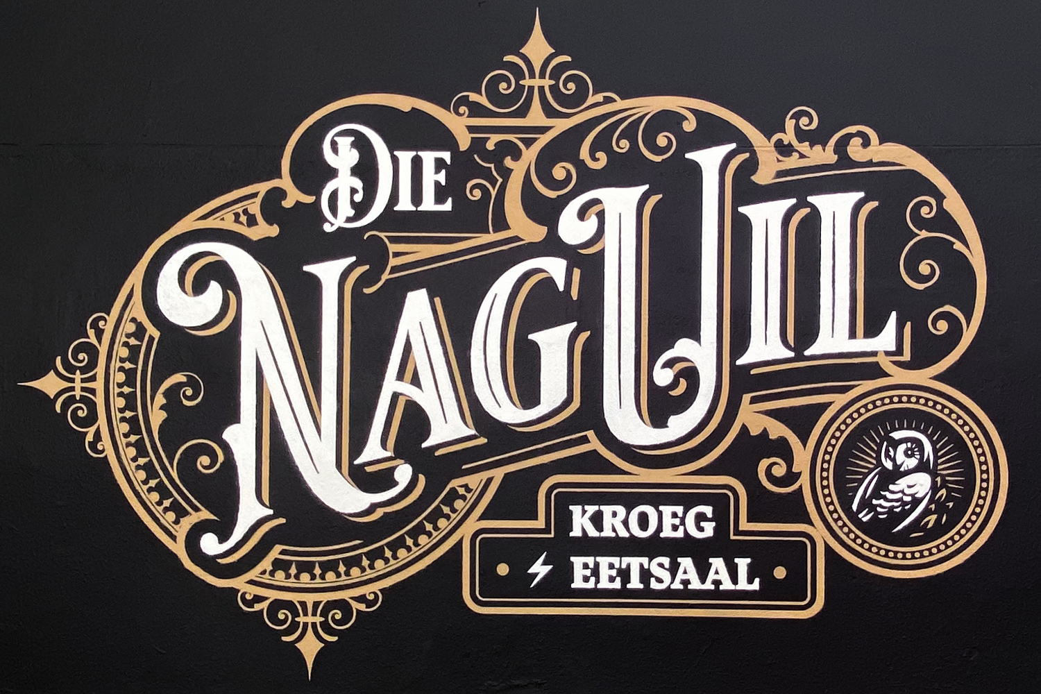 Ornate vintage-style sign with the words 'Die Naguil' and 'Kroeg Eetsaal' featuring decorative scrollwork and an illustration of an owl.