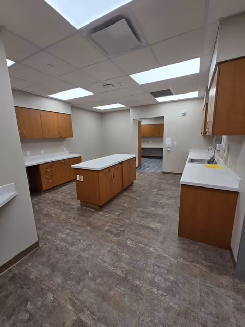 A spacious, empty room featuring wooden cabinets and counters along the walls.