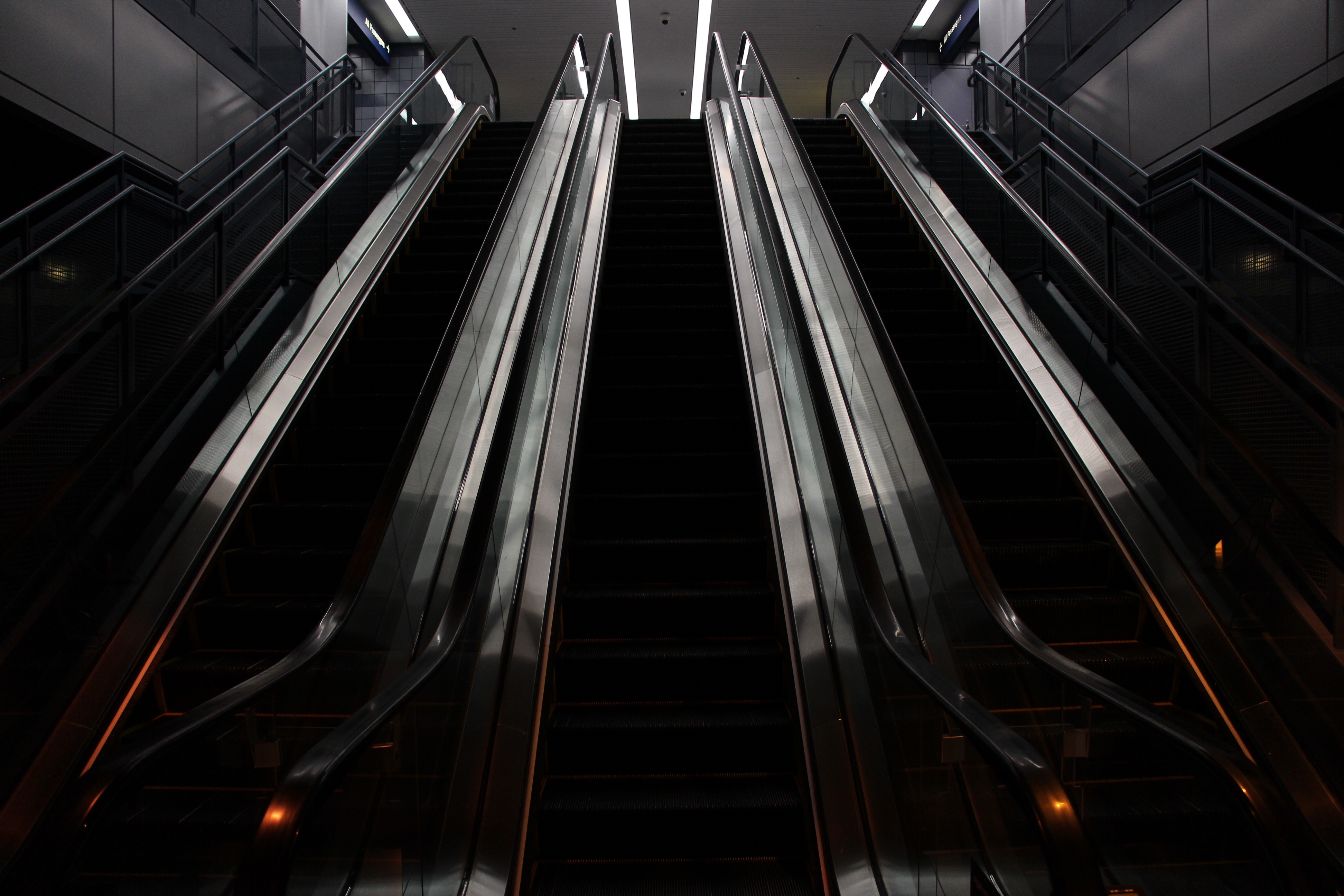 Dark escalators ascending in modern building symbolising leadership growth and strategic progress in public relations.