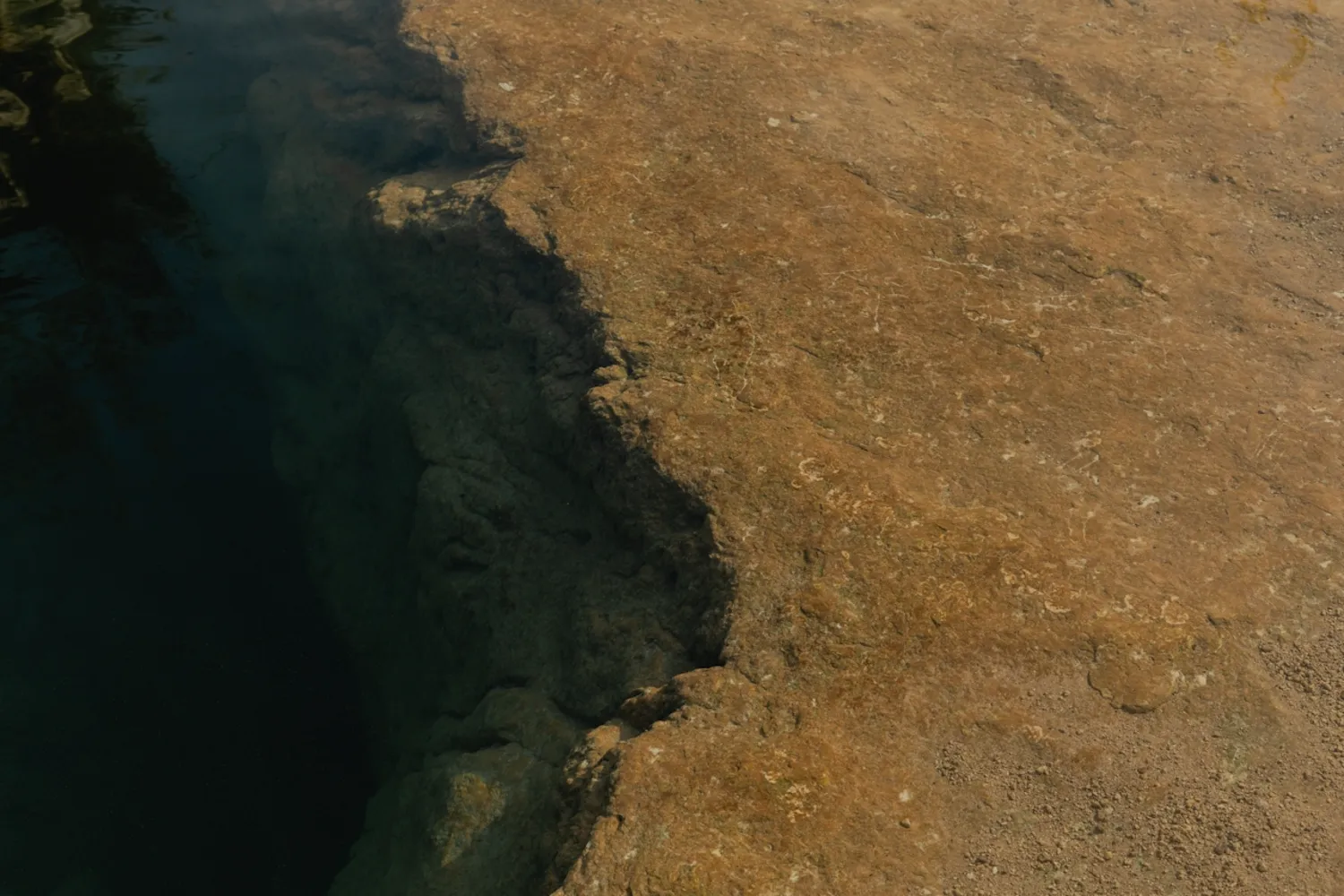 A large hole in the ground with a rocky cliff.