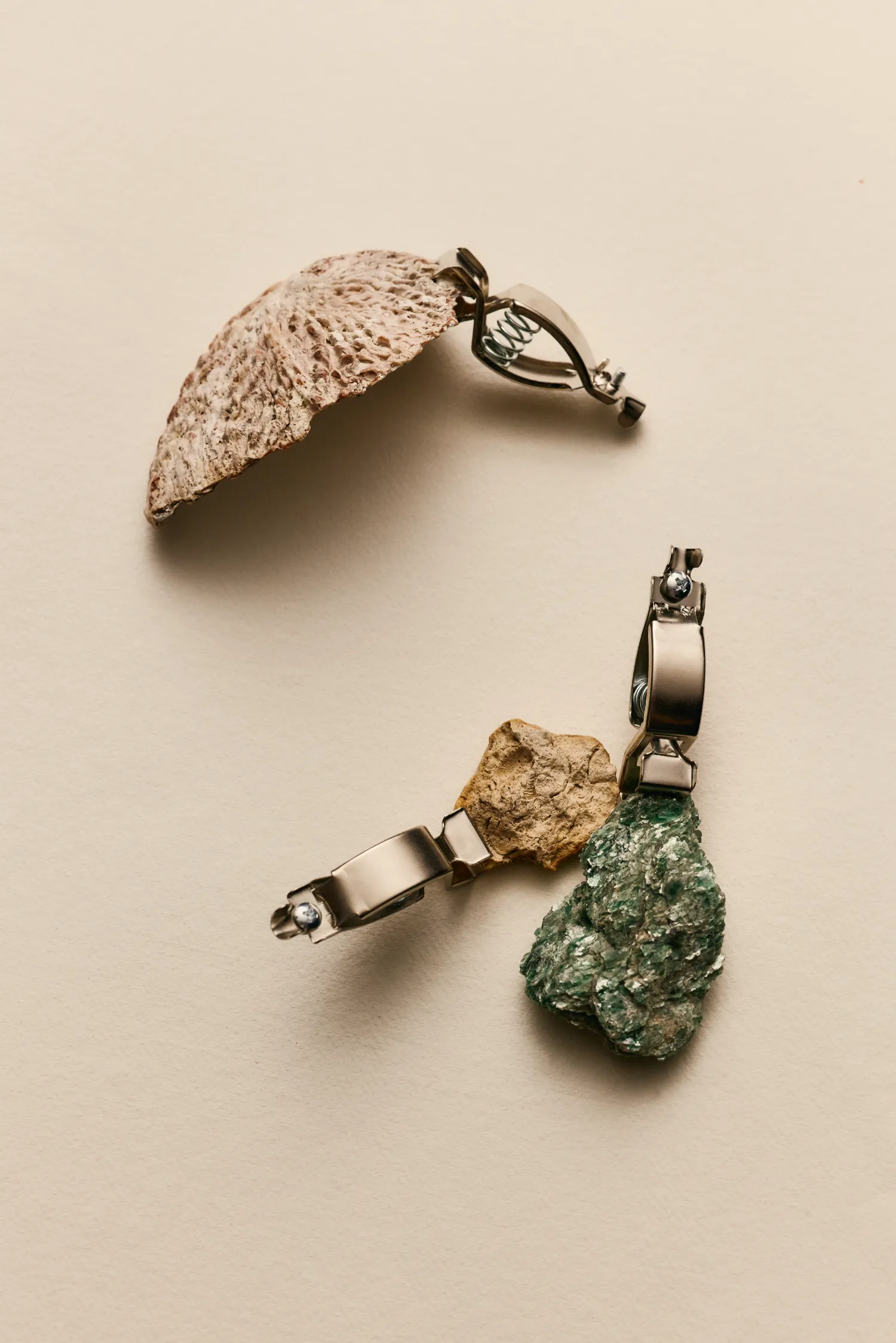 A silver chain with a leaf and a rock on it.