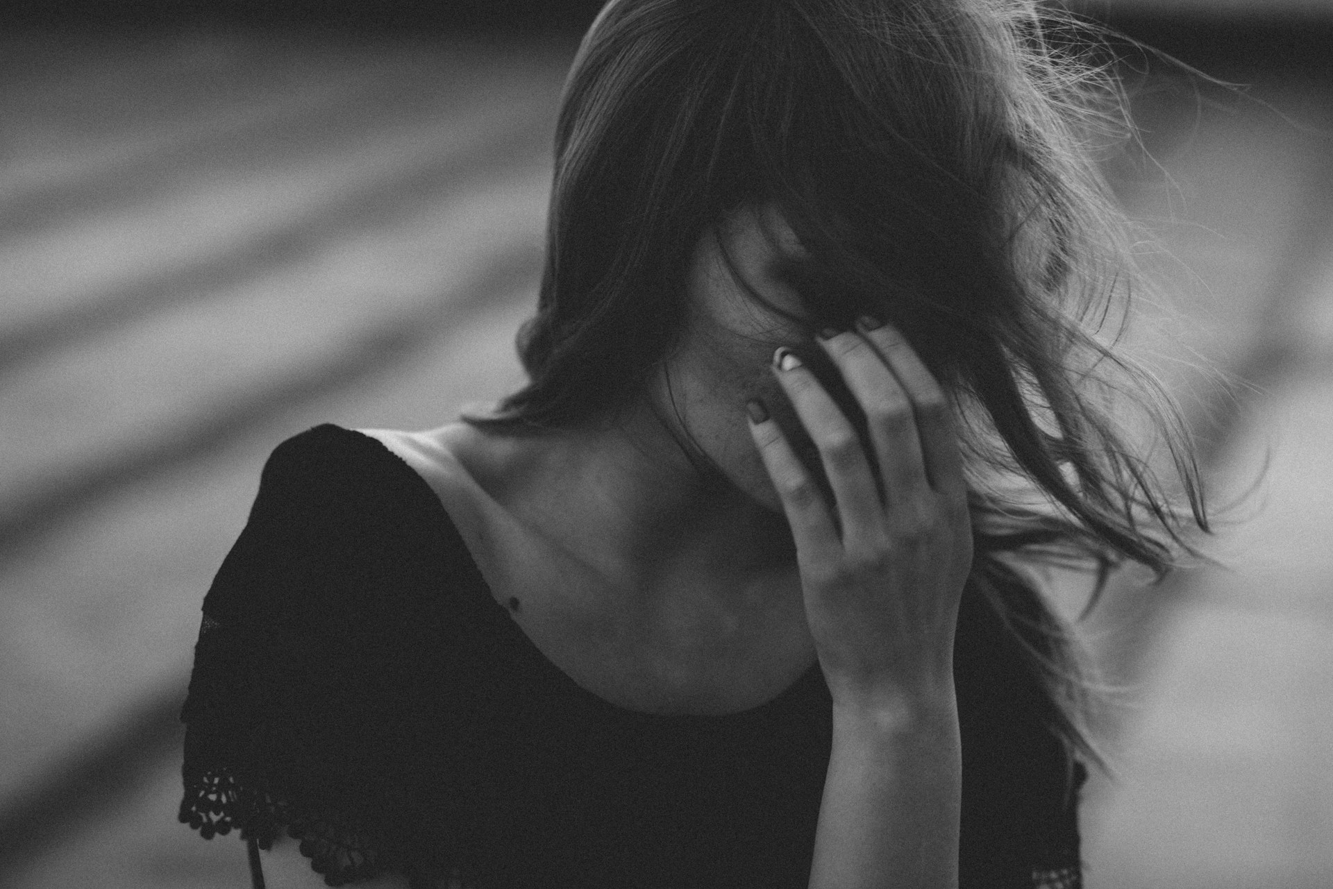 A grey and black photograph of a women covering her face