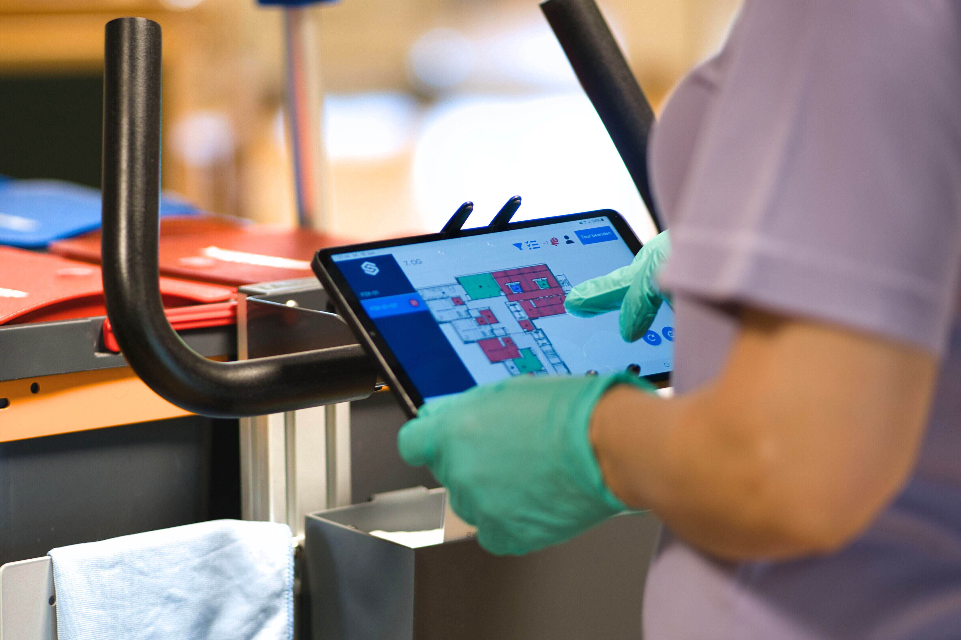 Tablet mit der soobr App wird von einer Reinigungskraft mit Handschuhen bedient.