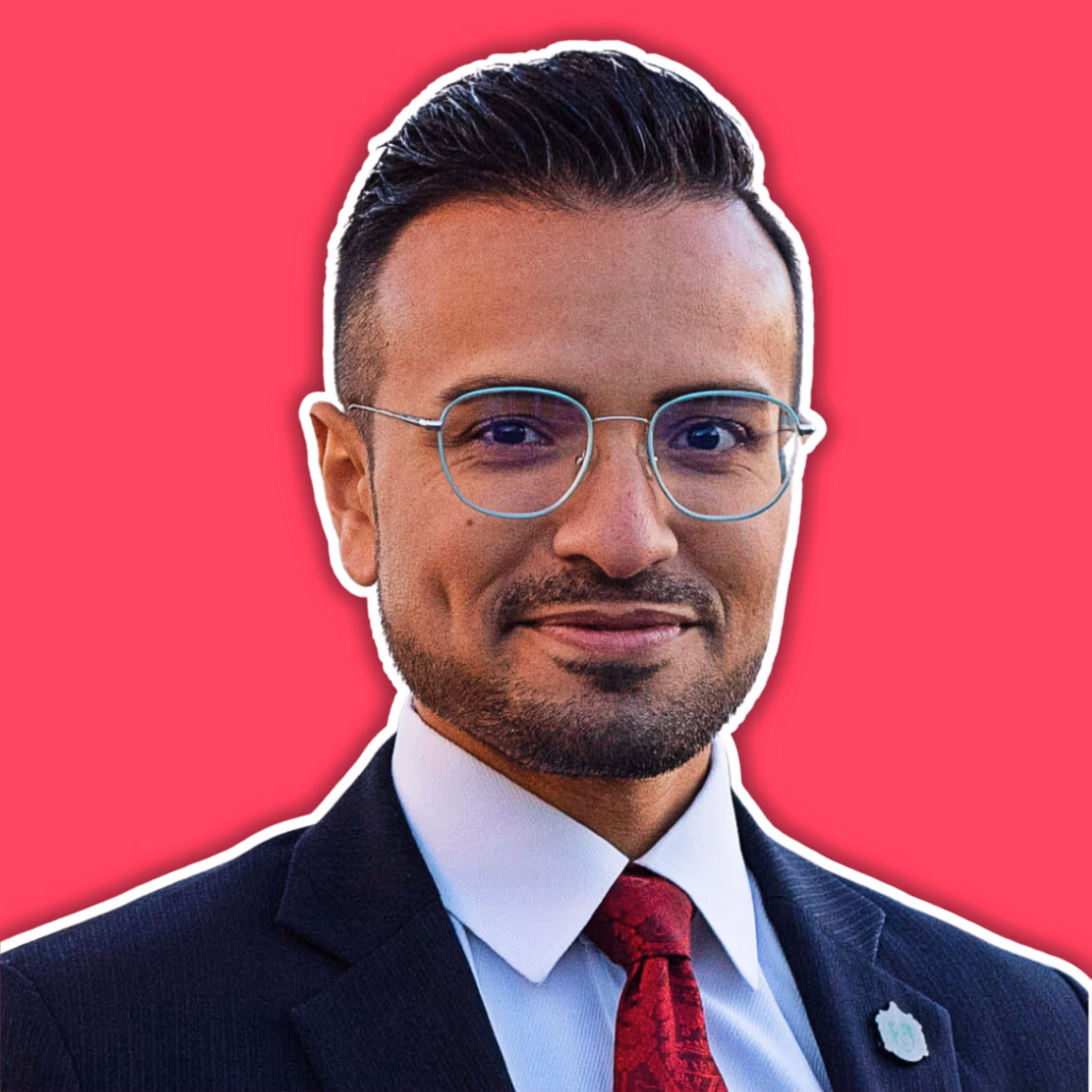 Man in glasses wearing a dark suit, white shirt, and red tie against a bright pink background.