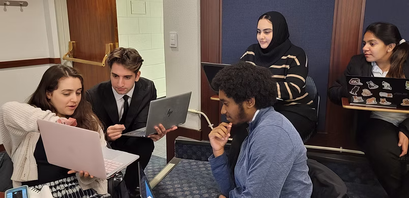 Sammy and her team working on the MTA & NJT design challenging. Sammy is showing her computer screen to the team.