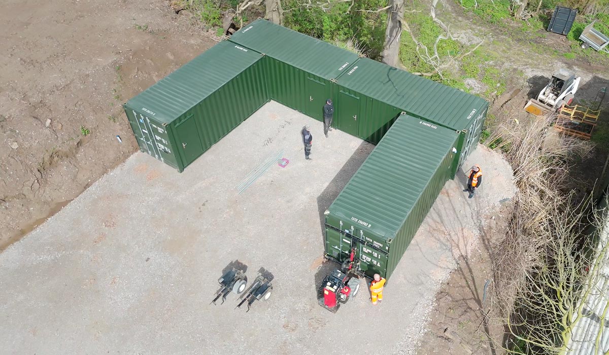 Aerial view of the installation team positioning green containers into a U-shaped compound on a gravel base