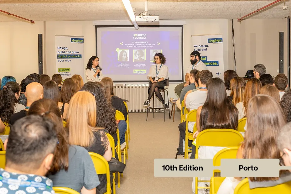 Speaker presenting to an audience at a UX community event with graffiti walls and a banner.