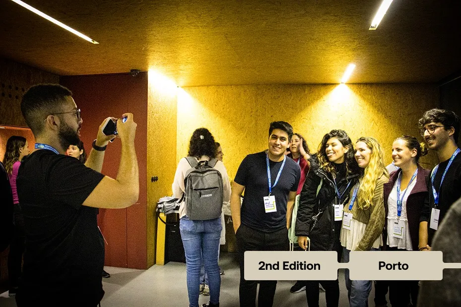 Three people wearing badges and casual clothes pose together indoors at a social event.