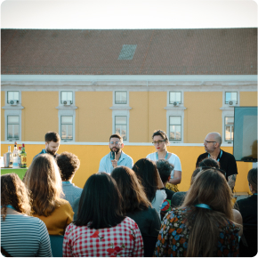 Hyphen members talking on a stage while the crowd is listening
