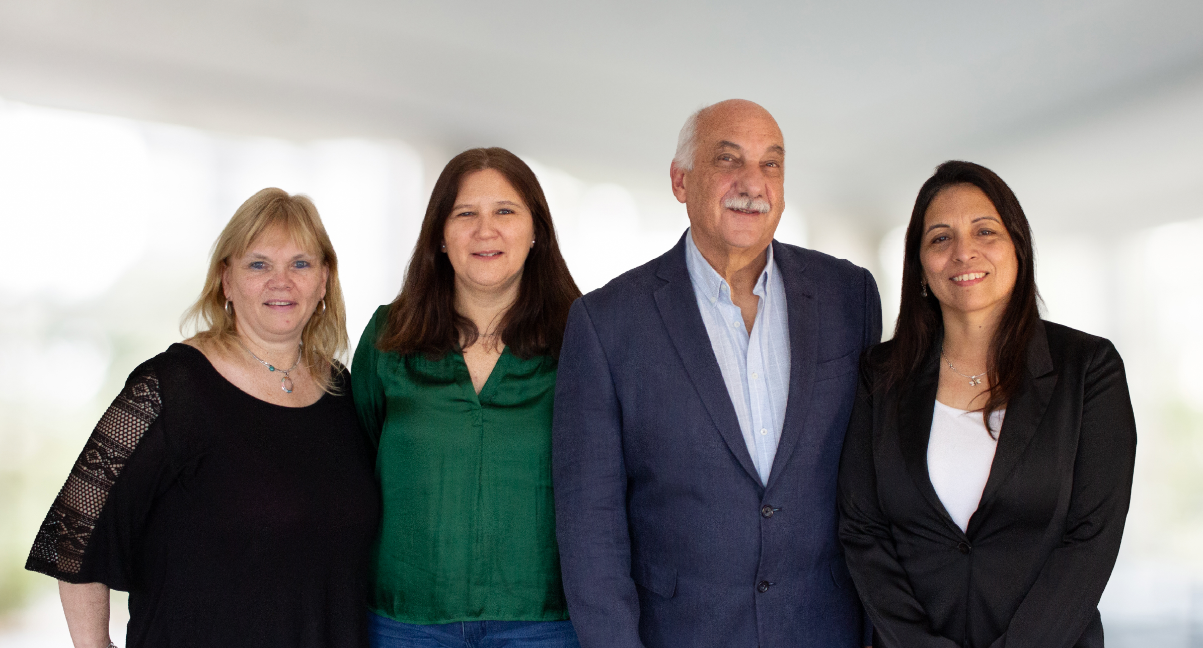 4 personas sonriendo a cámara. Tres mujeres y un hombre con vestimenta profesional.