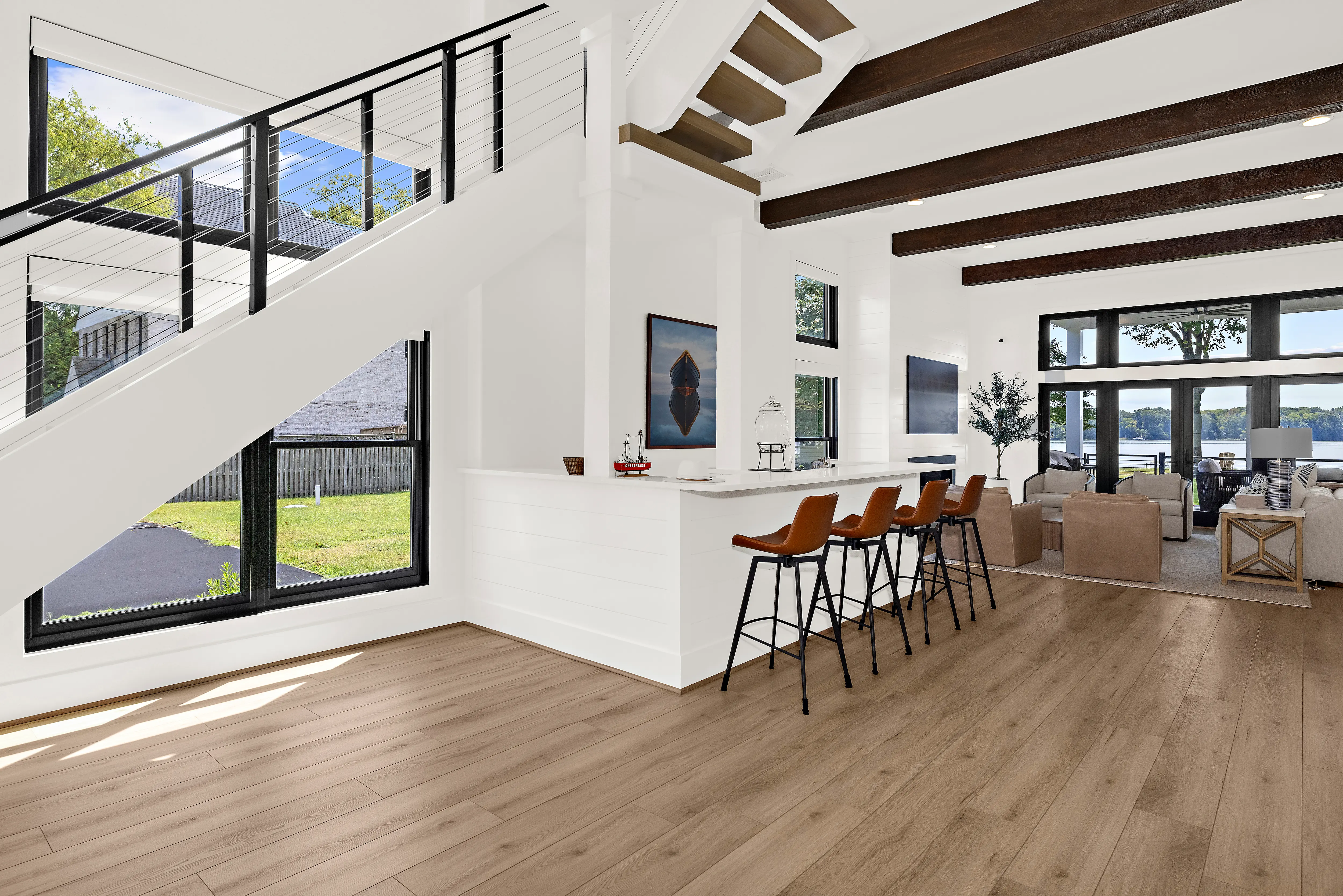 Cadle Creek - Rhode River completed home showing wet bar, open tread stairs, wood beams, living area, with wide glass doors leading to water view and porch.